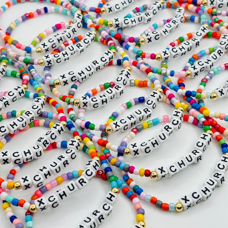 May include: A collection of elastic bracelets made from multicolored glass beads and white square plastic beads. Each bracelet features the text X CHURCH printed in black on the white beads, accented with small gold-toned metal spacer beads.