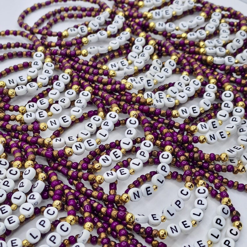 May include: A collection of beaded bracelets featuring alternating purple and metallic gold seed beads. Each bracelet includes white circular beads with the black printed letters N, E, L, P, and C, arranged to spell out the sequence NE LPC repeatedly.