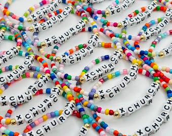 May include: A collection of colorful beaded bracelets featuring white square letter beads that spell out the word CHURCH, interspersed with small gold-toned metallic spacer beads. The bracelets are made from a variety of multi-colored plastic beads.