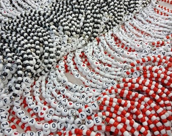 May include: A close-up of a variety of colorful beaded bracelets with letter beads spelling out words like "COFFEE", "LOVE", and "VAZZA".