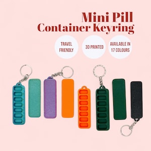 May include: Several mini pill container keyrings in different colours, such as teal, purple, orange, and green. Each container has a silver keyring attached. The image text reads "Mini Pill Container Keyring", "Travel Friendly", "3D Printed", and "Available in 17 Colours."