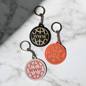 May include: Three keychains with a globe design and the text "WWW" in gold lettering. The globes are black, white, and orange.