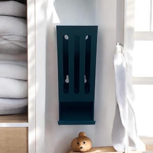 May include: A dark blue plastic wall-mounted organiser with three slots for storing items like plastic bags or other small items.