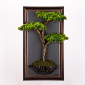 Peut inclure: Une œuvre d'art encadrée représentant un bonsaï. L'arbre a un tronc brun texturé et un feuillage vert vif. Il est placé sur un fond gris foncé dans un cadre marron. L'arbre est dans un pot décoratif et texturé.