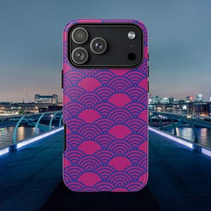 May include: A phone case with a vibrant pink and blue wave pattern. The case features a repeating design of blue semi-circles on a pink background. The phone case has a black camera module with three lenses.