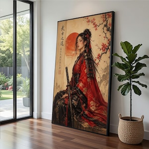 Op de afbeelding: Groot ingelijst kunstwerk met een vrouw in traditionele Japanse kledij, die een katana vasthoudt. Het kunstwerk heeft een rood-zwart kleurenschema, met kersenbloesems en een opkomende zon op de achtergrond. Japanse tekst is zichtbaar aan de linkerkant.