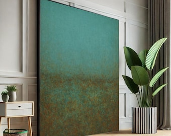 May include: Large abstract wall art with a teal and brown color palette. The artwork is framed in black and leans against a white wall. A potted plant with large green leaves sits nearby in a black and white striped pot.