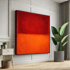 Op de afbeelding: Groot abstract schilderij met een gedurfd kleurblokontwerp. Het kunstwerk toont een levendige gradiënt van rode en oranje tinten, omlijst in zwart. Het schilderij wordt tentoongesteld op een witte muur, wat een moderne touch aan het interieur geeft.