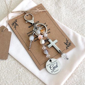 May include: A silver-toned metal keychain featuring a lobster clasp, a cross charm, and a round pendant engraved with the text 'BE STILL AND KNOW THAT I AM God PSALM 46:10'. The keychain is decorated with multi-colored beads and clear crystals.