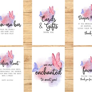 May include: Set of six white signs with watercolor butterfly and star accents. Text includes "Mom-osa Bar", "Cards & Gifts", "Diaper Raffle", "Pacifier Hunt", "We are enchanted to meet you!", and "Favors".