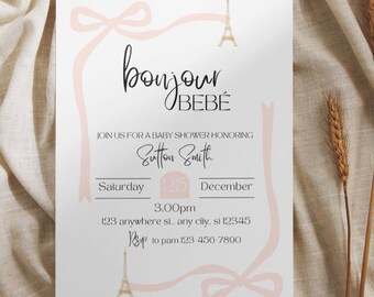 May include: A pink and white baby shower invitation with a gold Eiffel Tower graphic and the text "bonjour BEBE". The invitation includes the date, time, and location of the shower. RSVP information is also included.