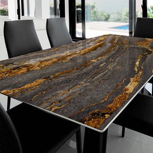 Può includere: Un tavolo da pranzo nero con un piano in marmo con un motivo a spirale grigio e oro. Il tavolo è circondato da sedie nere.