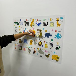 K&ouml;nnte beinhalten: Ein farbenfroher Alphabet-Chart mit Tieren und ihren Namen in Russisch. Der Chart ist auf wei&szlig;em Papier gedruckt und hat einen wei&szlig;en Hintergrund. Die Buchstaben sind in einer fetten, bunten Schriftart. Die Tiere sind im Cartoon-Stil illustriert.