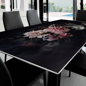 Può includere: Un piano da tavolo in vetro nero con un design floreale con fiori rosa, bianchi e viola. Il piano del tavolo è circondato da sedie nere.