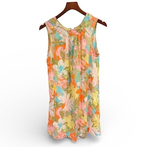 May include: A sleeveless floral top in a variety of colors, including pink, orange, yellow, blue, and green. The top is hanging on a wooden hanger. The fabric appears to be lightweight and semi-sheer, with a floral pattern.