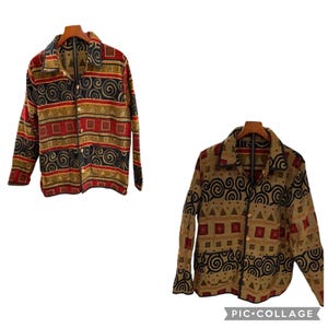 May include: Two button-down shirts with a colorful geometric pattern. The shirts feature a mix of red, gold, black, and tan colors. The design includes squares, triangles, and spiral shapes. The shirts are displayed on wooden hangers.