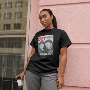 May include: A black t-shirt with a vintage Jet magazine cover featuring a photo of Muhammad Ali and Malcolm X. The magazine cover text reads "Alabama News,  W.L.  Norton  Running  For U.S. Congress,  Will Link With Malcolm X,  Celebrates  King's  Birthday".