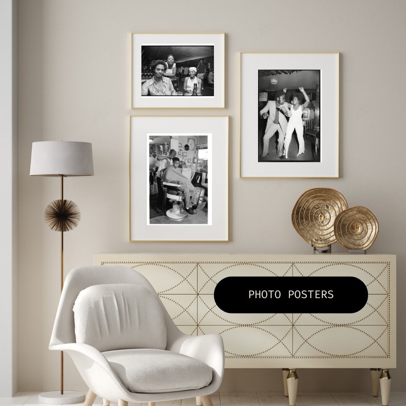 May include: Three black and white framed photographs of people in various settings. The photos are hanging on a white wall above a white dresser with a geometric pattern. The dresser has a gold metal decorative stand with a round top and three legs. The stand is holding two gold metal decorative plates. The dresser is also topped with a white armchair. The text "PHOTO POSTERS" is printed on a black rectangle in the center of the dresser.