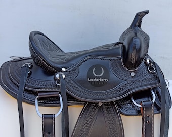 May include: Black leather western saddle with tooled detailing and a silver concho. The saddle has a  "Leatherberry" logo on the seat.