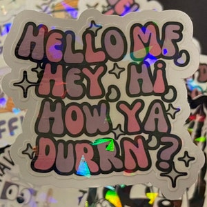 May include: A holographic sticker with a pink and purple color scheme. The sticker says "Hello, hey, hi, how ya doin'?" with stars around the text.