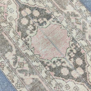 May include: A vintage rug with a faded pink and gray floral pattern. The rug has a distressed look and is made of a soft, woven material.