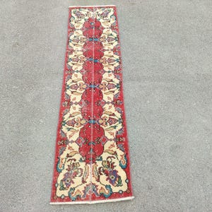 May include: A red, white and blue runner rug with a floral pattern. The rug has a traditional design with intricate details.