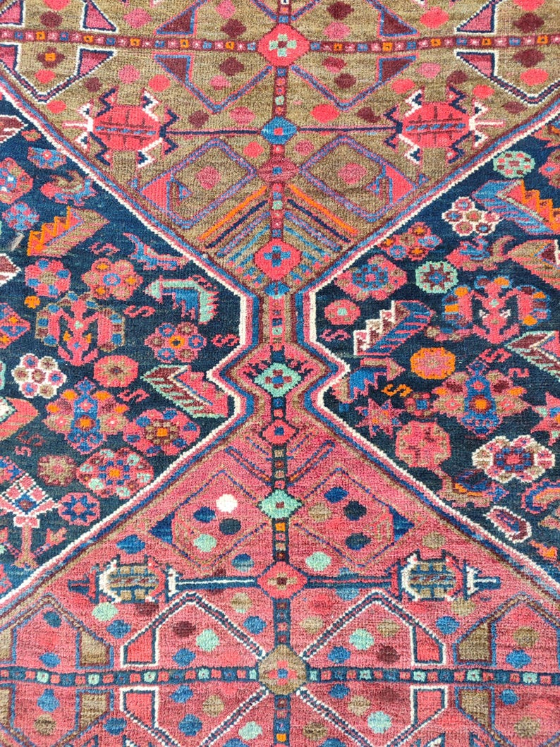 May include: A vintage rug with a geometric pattern in shades of red, blue, green, and brown. The rug has a central diamond shape with smaller diamonds and other geometric shapes surrounding it.