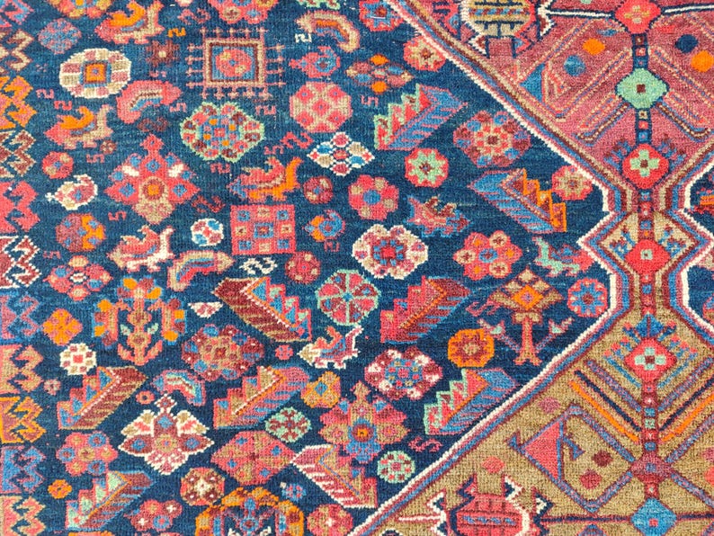 May include: A close-up of a colorful rug with intricate patterns in shades of red, blue, and beige. The rug features a geometric design with floral motifs and a central medallion.