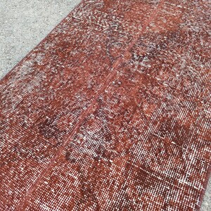 May include: A distressed red and white rug with a woven texture. The rug has a faded, vintage look.