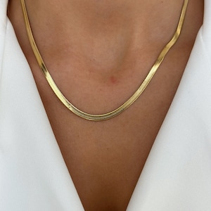 Puede incluir: Un collar de cadena de oro con un diseño de cadena de serpiente.