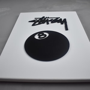 May include: White canvas with a black 8-ball and the word "STUSSY" in black lettering.