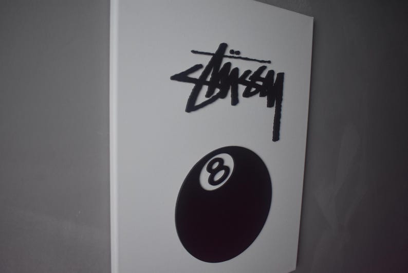 May include: A black and white canvas print featuring the Stussy logo and a black 8-ball.