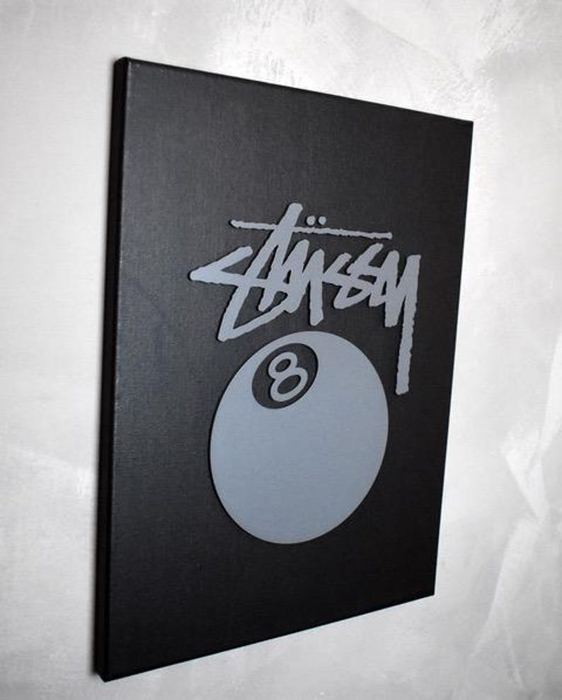 May include: A black canvas print with a gray 8-ball and the word "STUSSY" in a stylized font.