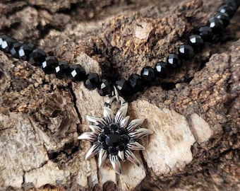 Collier traditionnel avec pendentif edelweiss orné de strass noirs. Perles noires. Une chaîne d'extension phare 42/47 cm
