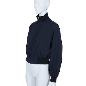 May include: A navy blue bomber jacket with a black collar, cuffs, and waistband. The jacket features a front zip and a relaxed fit. The long sleeves are slightly gathered at the cuffs. The jacket is displayed on a mannequin.