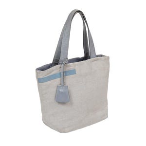 May include: A light gray canvas tote bag with a light blue leather trim and handles. The bag has a small light blue leather tag attached to the handle.