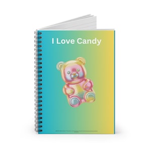 Op de afbeelding: Spiraalgebonden notitieboek met een kleurrijke omslag. De omslag toont de tekst "I Love Candy" boven een gummybeer-illustratie. De gummybeer is een mix van roze, geel en blauw. De achtergrond loopt over van blauw naar geel.