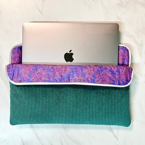 Housse d'ordinateur Velours Côtelé couleur Vert Sapin et sa doublure Liberty violette motif cachemire.
C'est aussi un accessoire iPad et tablette.
On voit un macbook Pro Apple qui sort à moitié de la housse AMMA