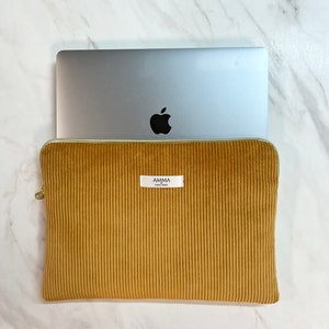 Housse d'ordinateur Velours Côtelé Moutarde - Résistante & Douce - Dispo IPad et tablette.
Un macbook pro Apple dépasse de la pochette