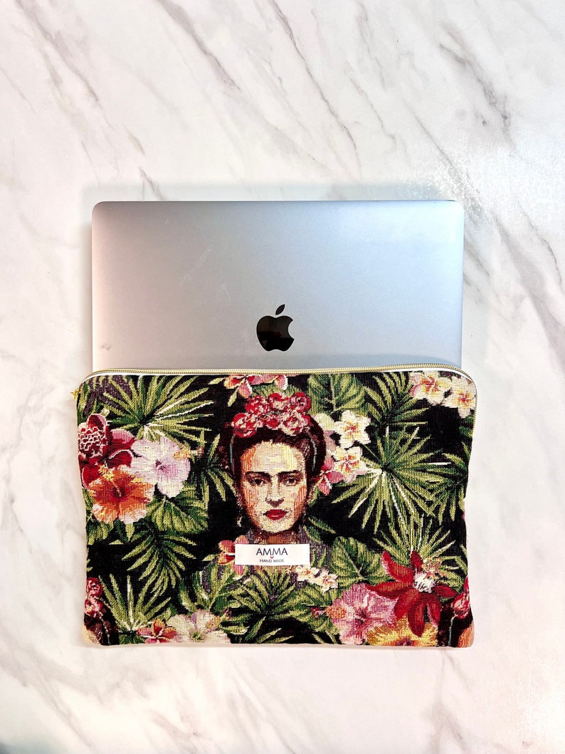 Housse ordinateur Frida Khalo en tissu Jacquard. Un PC portable MacBook Pro Apple se trouve dans la pochette.