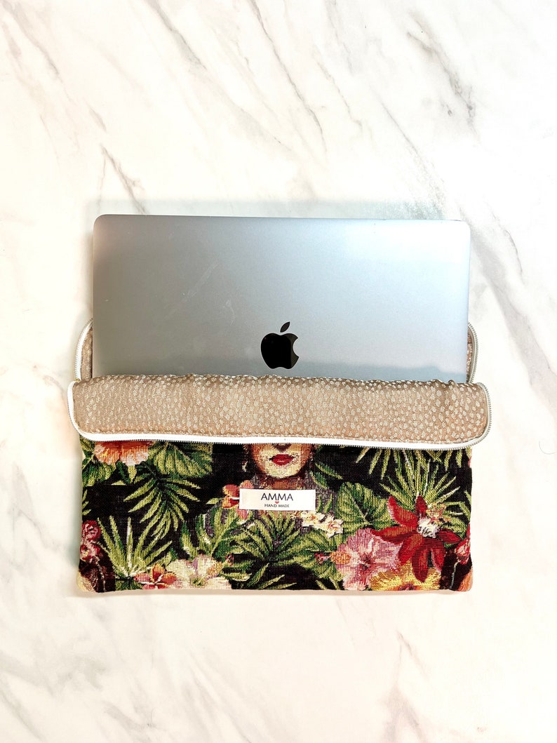 Housse ordinateur Frida Khalo en tissu Jacquard. Un PC portable MacBook Pro Apple se trouve dans la pochette.