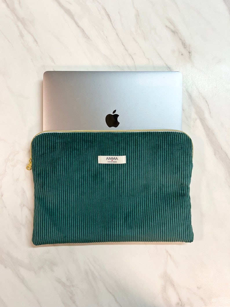 Housse ordinateur Velours Côtelé couleur Vert Sapin. Accessoire iPad et tablette.
On voit un macbook Pro Apple qui sort à moitié de la housse AMMA