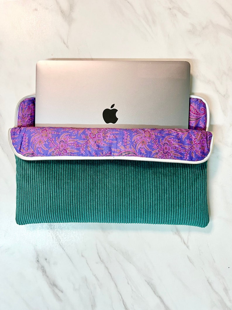 Housse d'ordinateur Velours Côtelé couleur Vert Sapin et sa doublure Liberty violette motif cachemire.
C'est aussi un accessoire iPad et tablette.
On voit un macbook Pro Apple qui sort à moitié de la housse AMMA