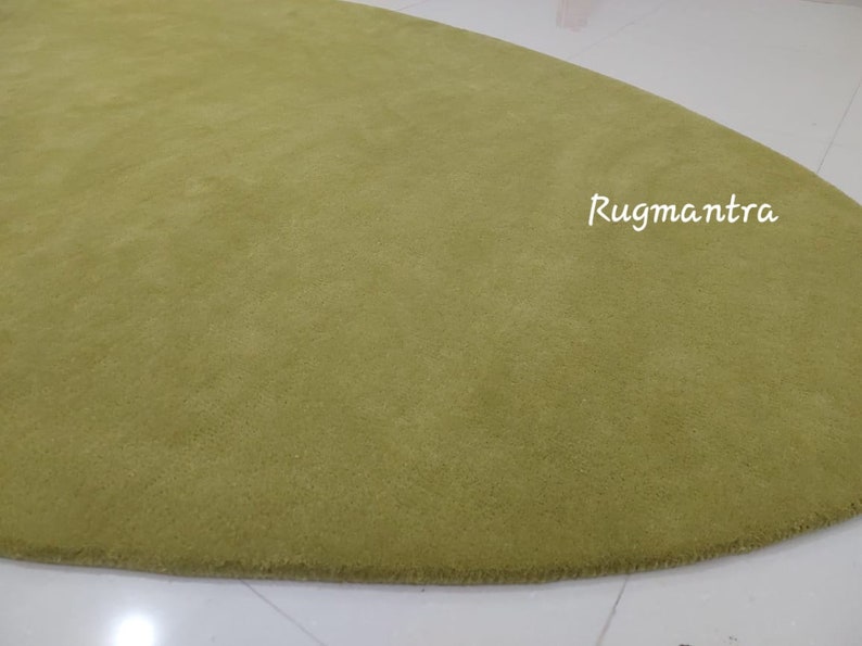 May include: A large, oval-shaped, green rug with a soft, plush texture. The rug is made of high-quality materials and is perfect for adding a touch of elegance to any room.