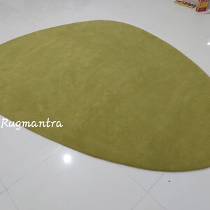May include: A large, green, oval-shaped rug with a soft, plush texture. The rug is made of a high-quality material and is perfect for adding a touch of color and comfort to any room.