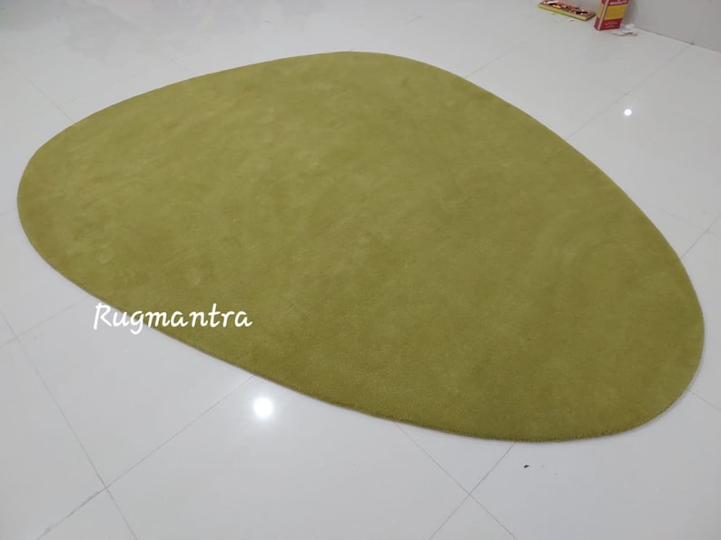 May include: A large, green, oval-shaped rug with a soft, plush texture. The rug is made of a high-quality material and is perfect for adding a touch of color and comfort to any room.