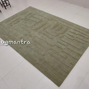 May include: A green area rug with a textured, geometric pattern. The rug has a modern, contemporary design.