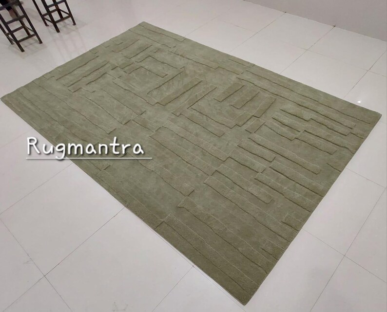 May include: A green area rug with a textured, geometric pattern. The rug has a modern, contemporary design.