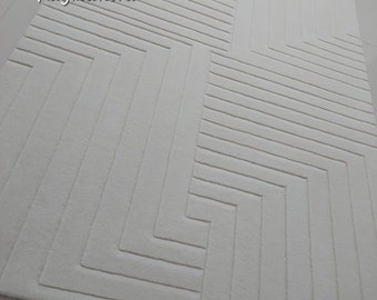 May include: White rug with a geometric pattern of raised lines. The pattern is made up of a series of overlapping rectangles and squares.