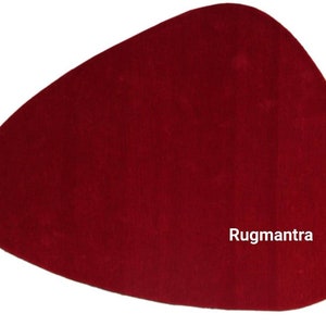 May include: A solid red, free-form shaped rug with the text "Rugmantra" in white lettering.